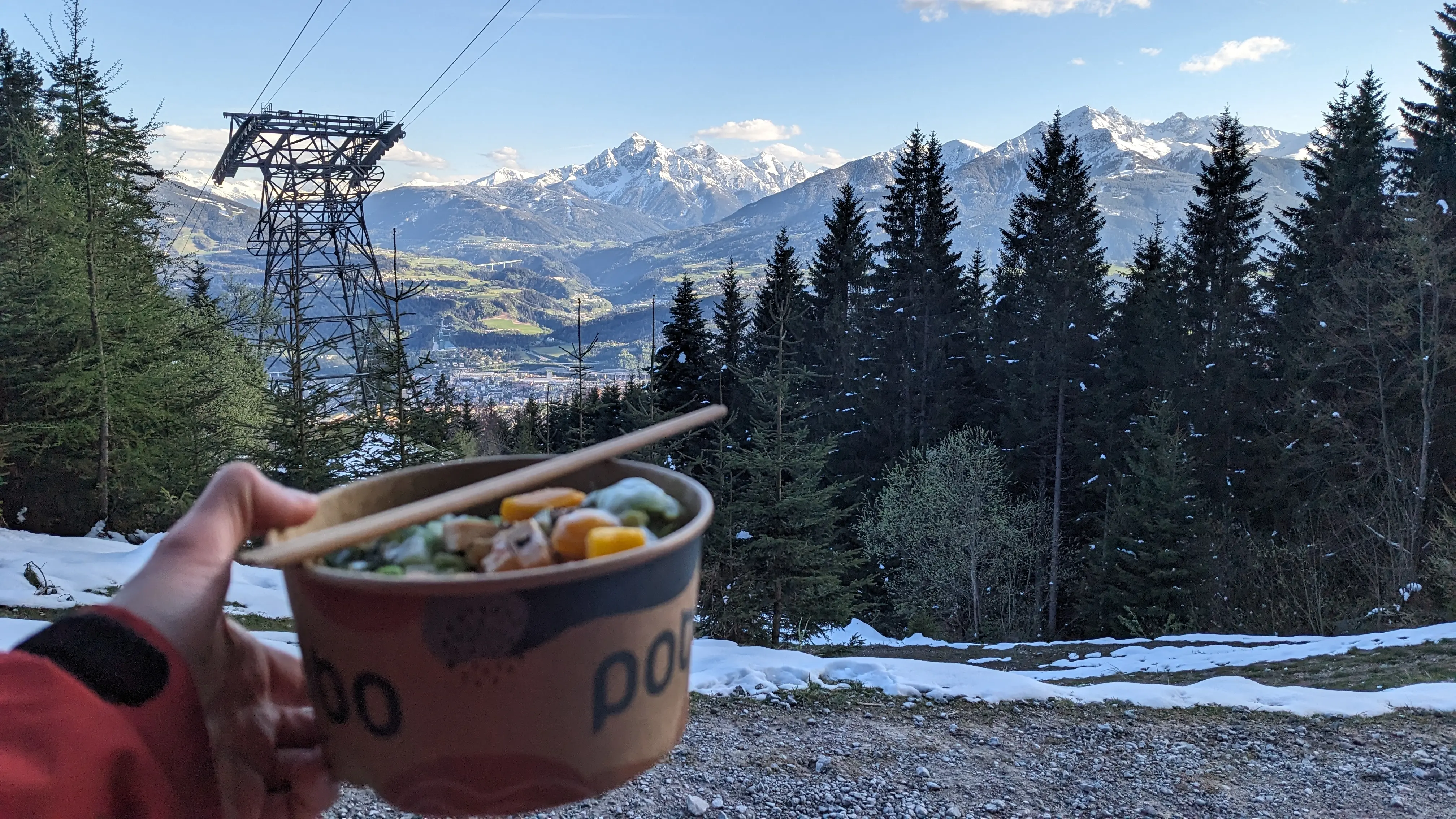 A poke bowl being held before a view of the mountain